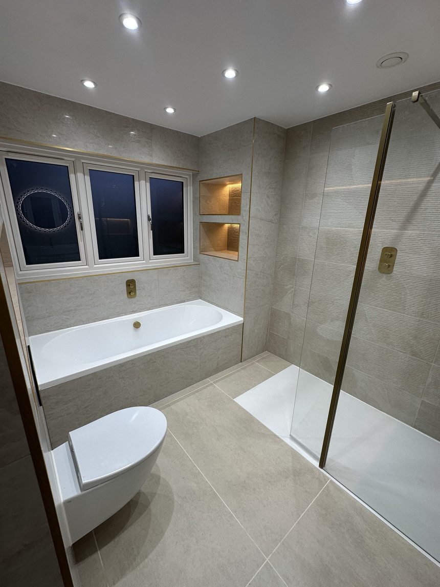 Finished bathroom by Andrade Renovations — grey marble tiling, brushed-gold fittings and lit niches