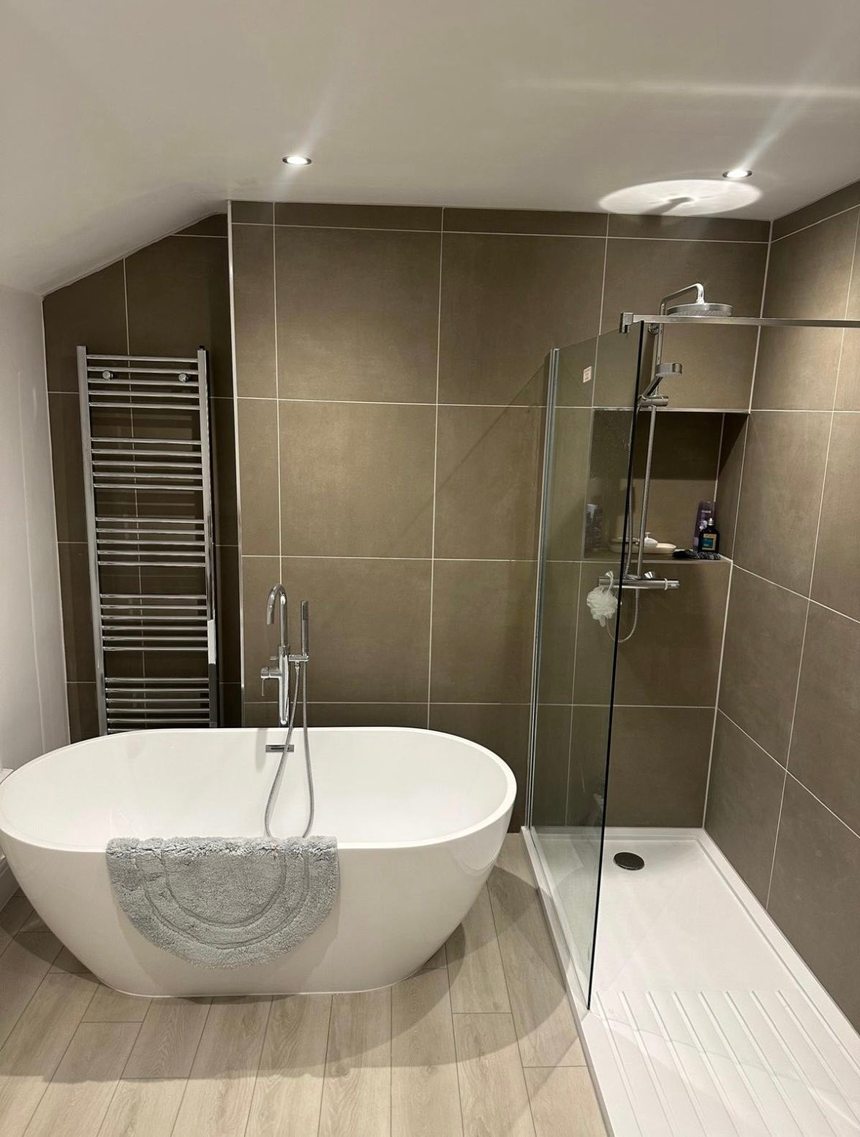 Finished bathroom with a freestanding bath and walk-in shower by Andrade Renovations